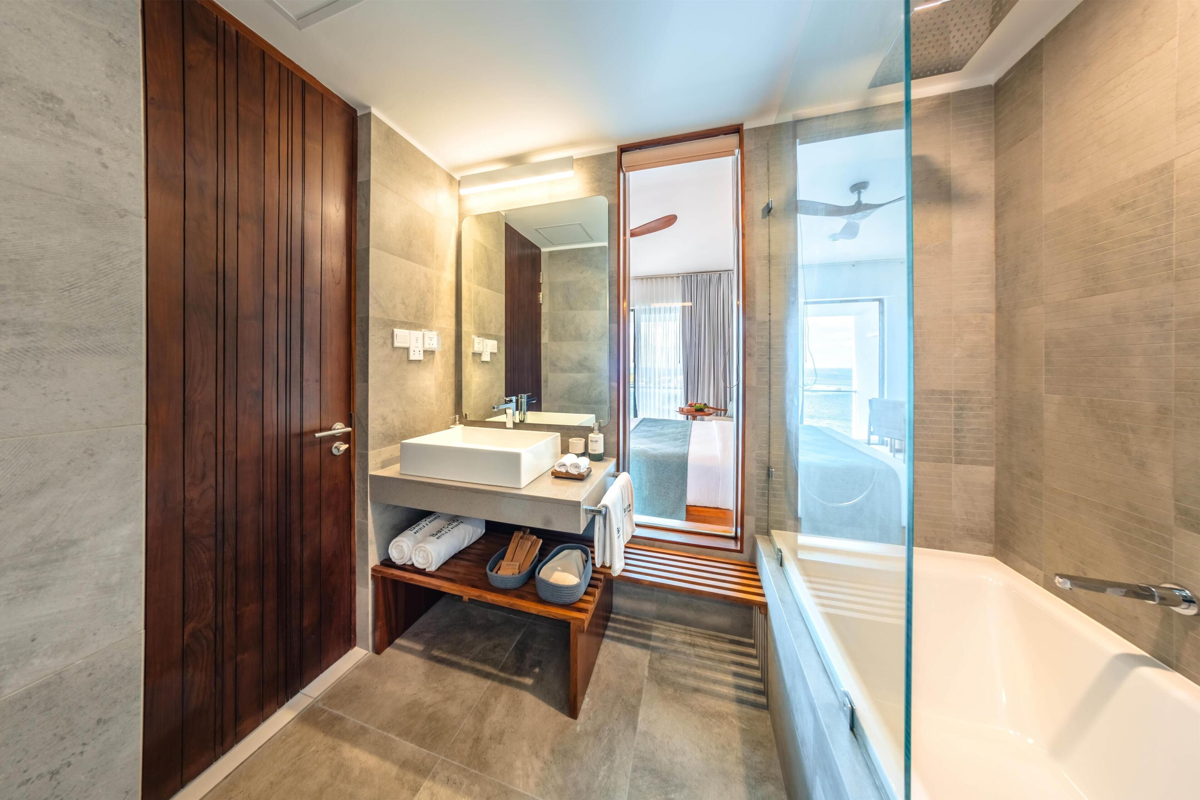 A modern bathroom with a wooden wardrobe, a sink with a mirror, a bathtub, and a shower area.