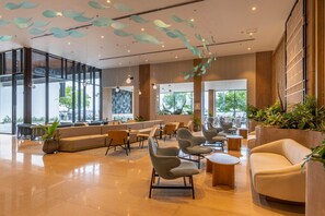 A modern lobby with a seating area, large windows, and decorative ceiling elements.