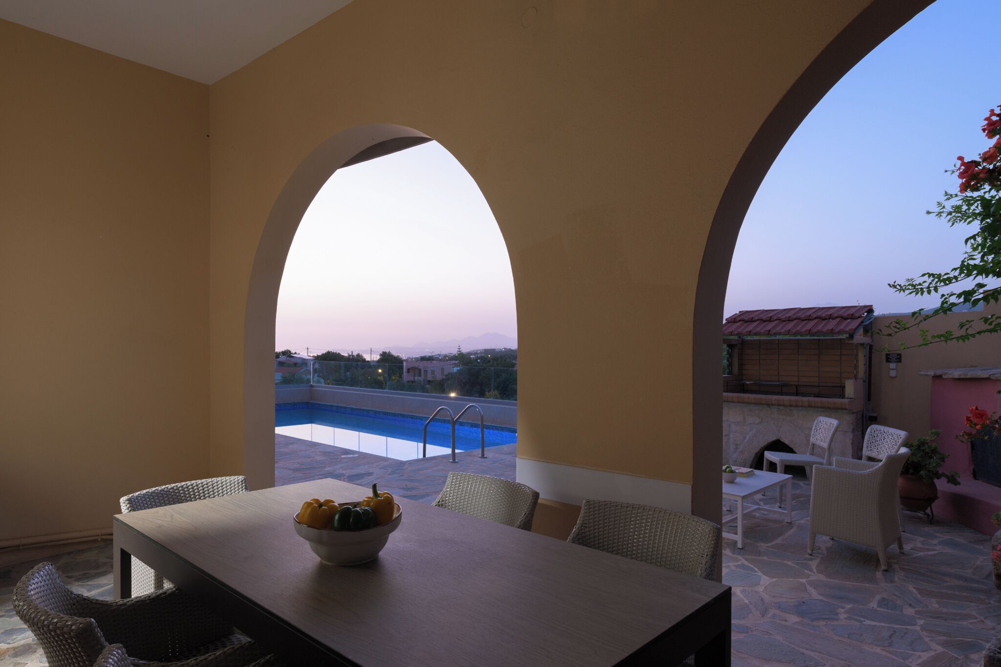 Un área de comedor al aire libre con vista a una piscina y un patio de piedra.
