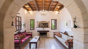 A spacious living room with a fireplace, two sofas, a coffee table, and a chandelier. - Abrakamus By Forest Villas (Rethymno)