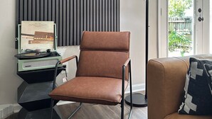 A modern living room with a brown leather chair, a vintage record player, and a tall floor lamp. - Midtown Urban Retreat- Family Friendly 3BR Retreat (Tallahassee)