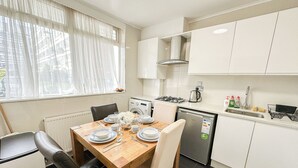 A modern kitchen with a dining table set for four, a built-in oven, and a dishwasher.