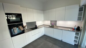 Una cocina moderna con armarios blancos, una estufa negra y una encimera gris.