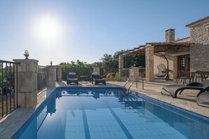 En swimmingpool med solstolar och en pergola.