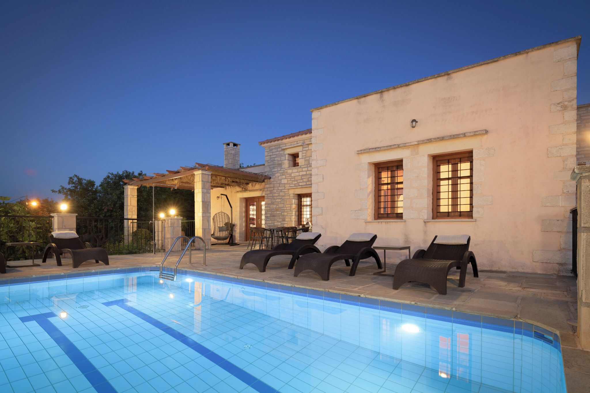 A swimming pool with lounge chairs and a stone building with windows.