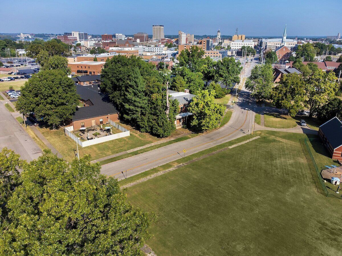 Luchtbeeld van een stadsgezicht met een groot groen park, gebouwen en een kerktoren.