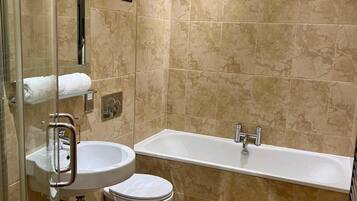 A bathroom with a glass shower enclosure, a sink, a toilet, and a bathtub.