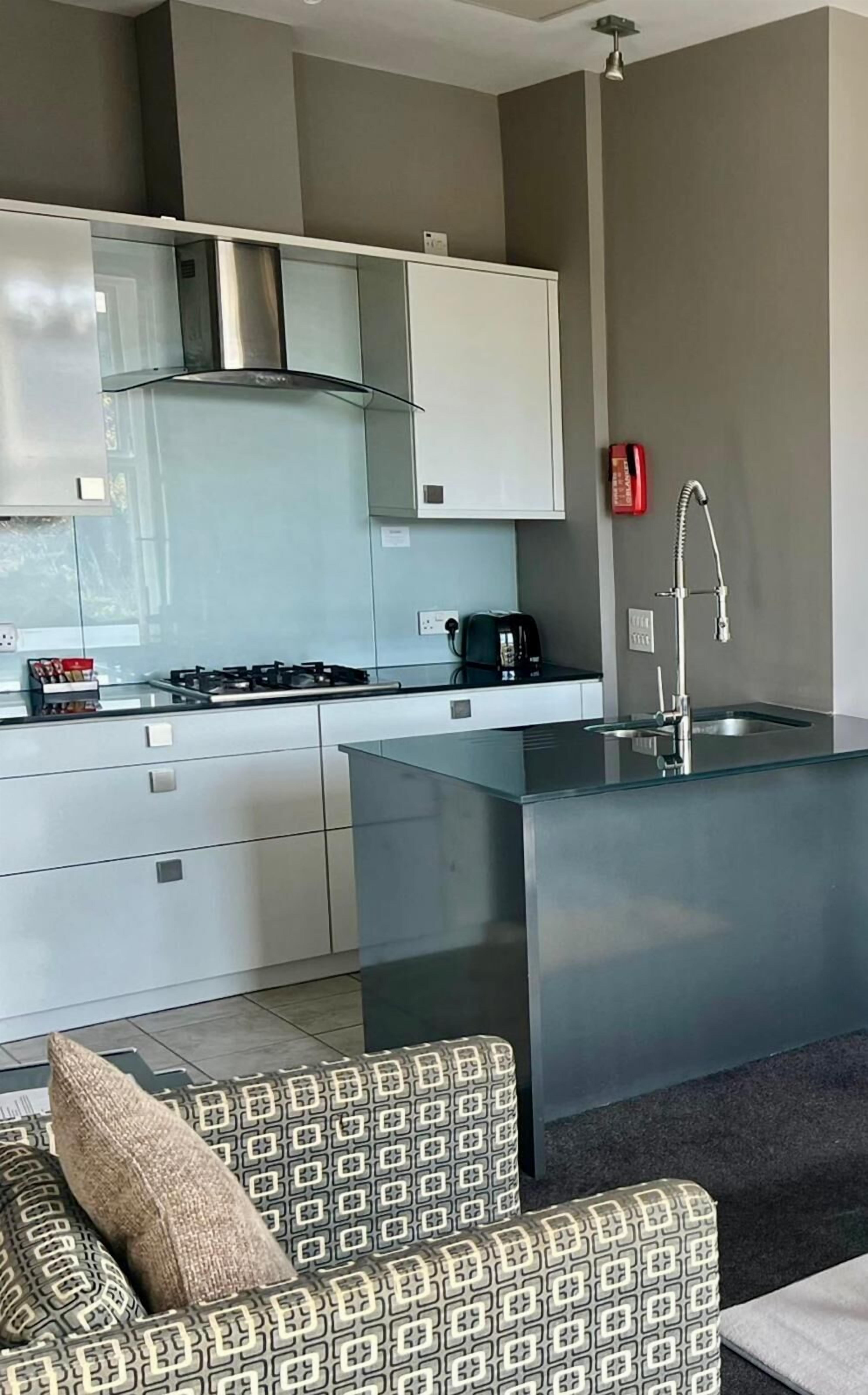 Una cocina moderna con armarios blancos, una campana extractora de acero inoxidable e isla integrada con un lavamanos.