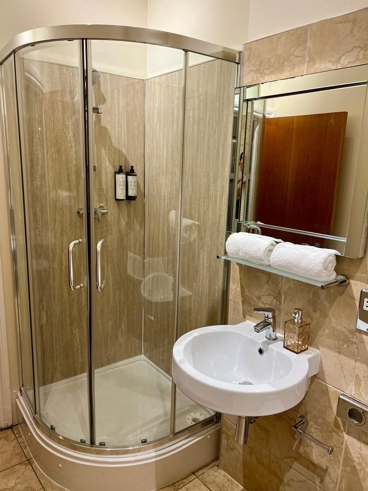 A modern bathroom with a glass-enclosed shower, a white sink, and a wooden vanity.