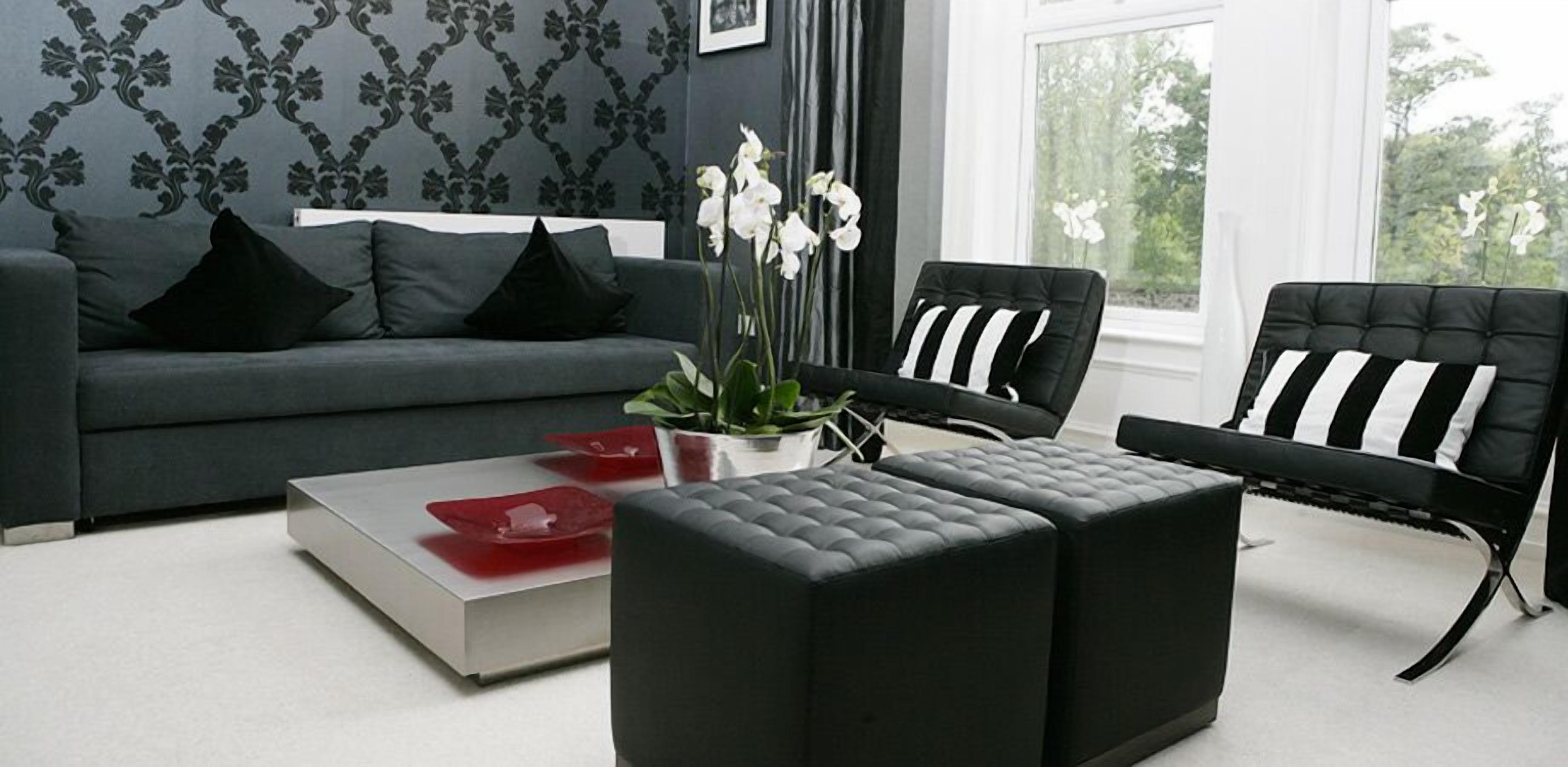 Una sala de estar moderna con un sofá gris, un sillón a rayas negras y blancas y un reposapiés negro.