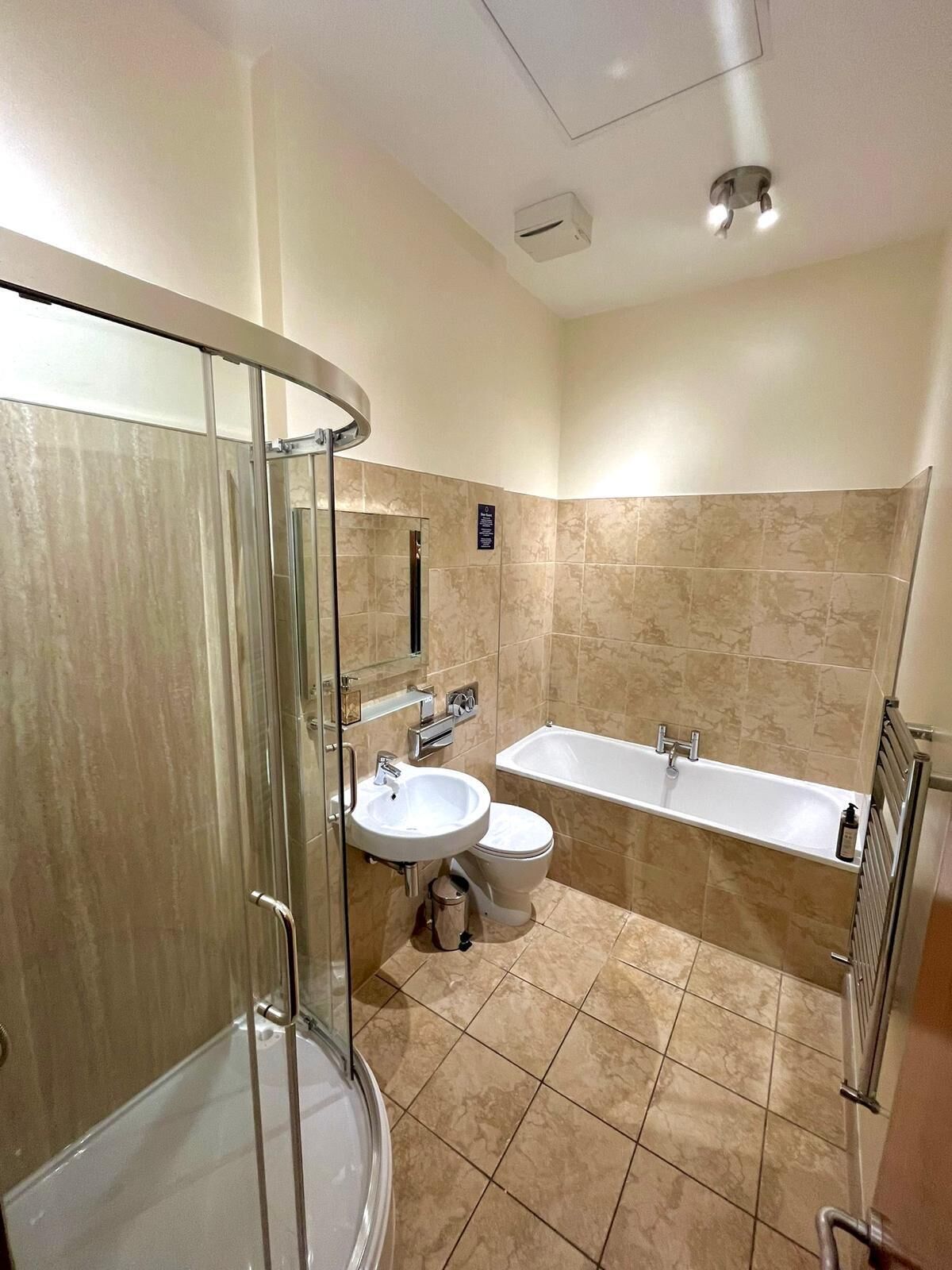 A modern bathroom with a glass shower enclosure, a sink, toilet, and a bathtub.