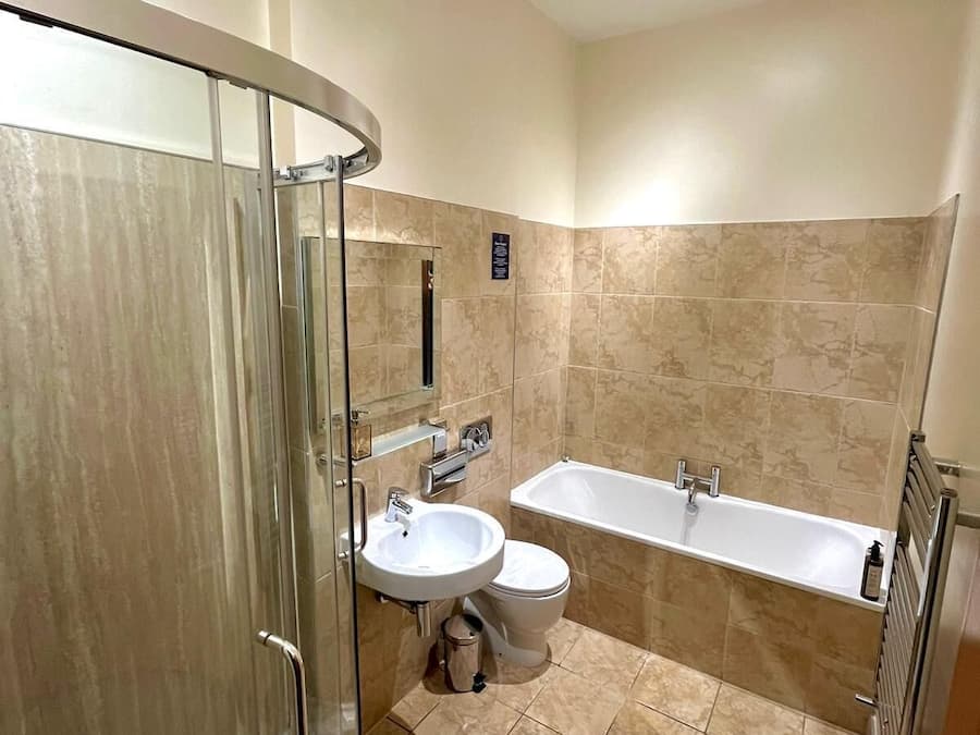 A modern bathroom with a glass shower enclosure, a sink, toilet, and a bathtub.