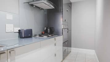 Una cocina moderna con estufa a gas, cafetera y campana extractora de acero inoxidable.