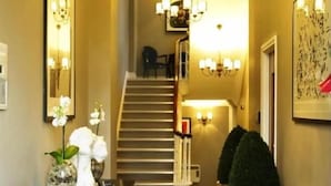 Ein Flur mit Treppe, einem Essbereich mit Tisch und Stühlen sowie Wandleuchten.