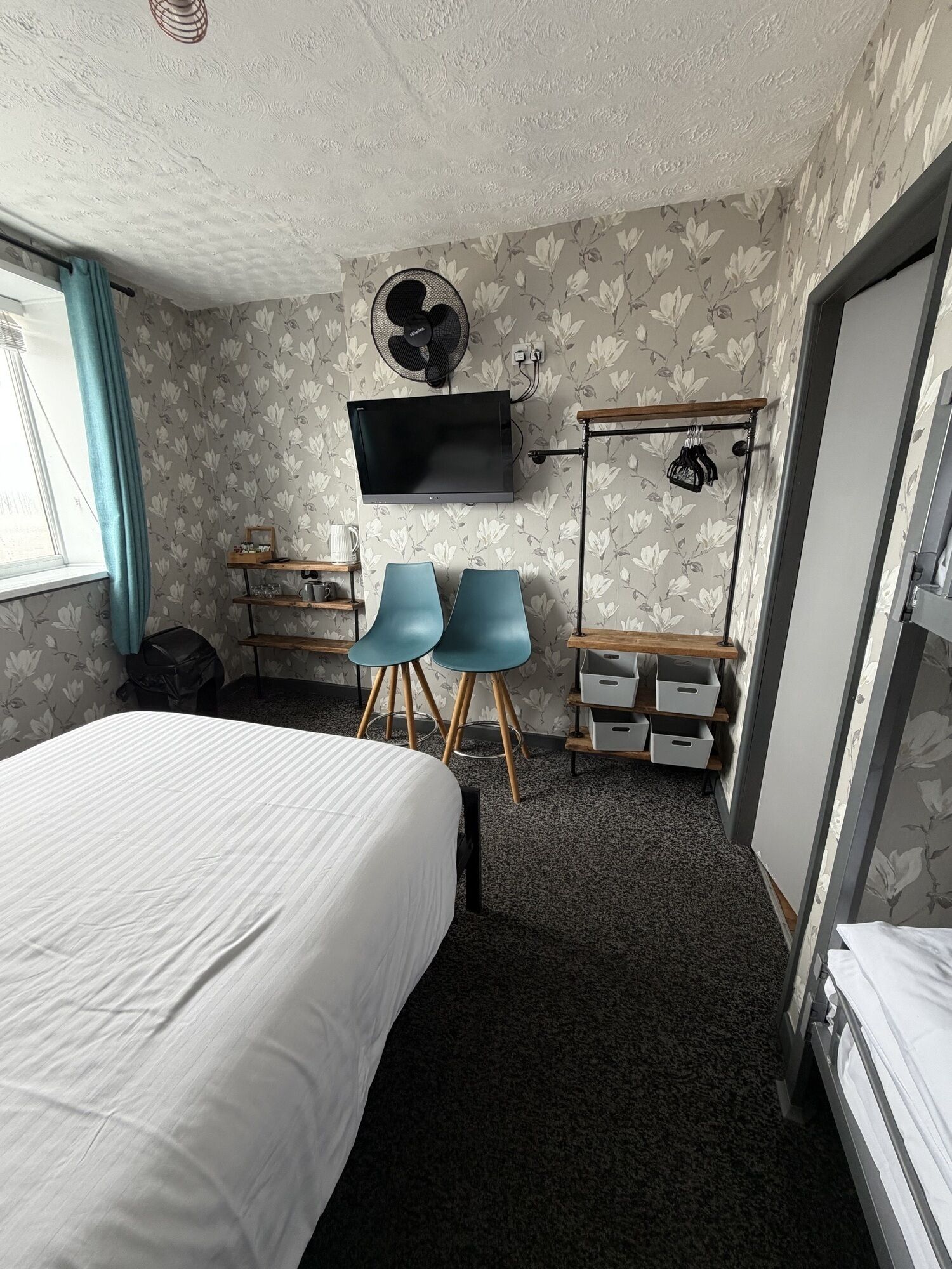 Une chambre d’hôtel de taille réduite, comprenant un lit, deux chaises, un bureau, une télévision et une armoire.
