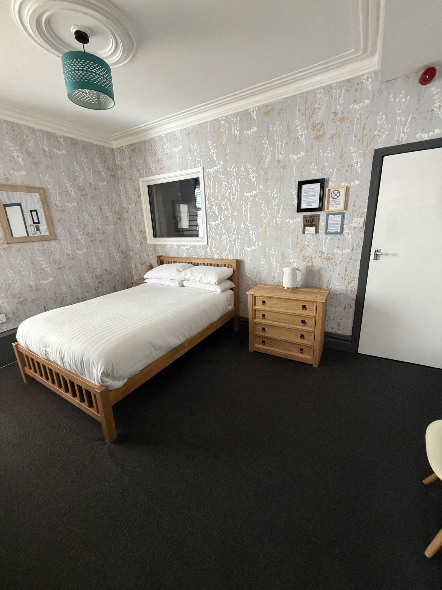 Une chambre à coucher avec un lit, une commode, un miroir et une porte.