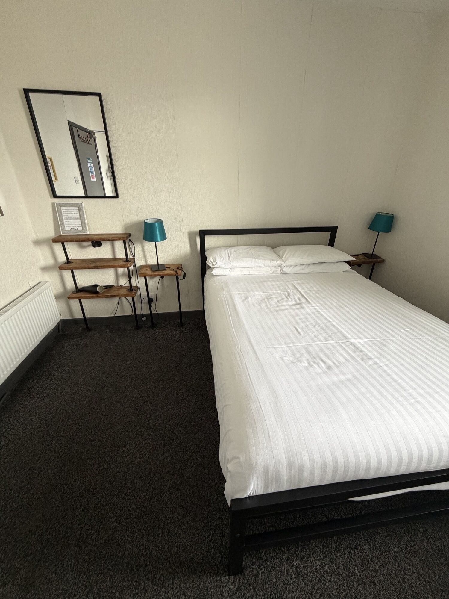 A single bed with white bedding in a room with a carpeted floor.