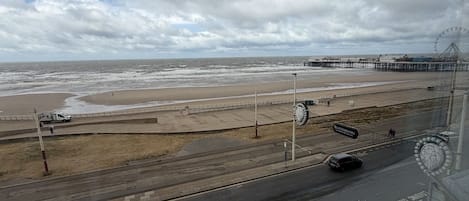 A coastal road with a beach and pier in the background.