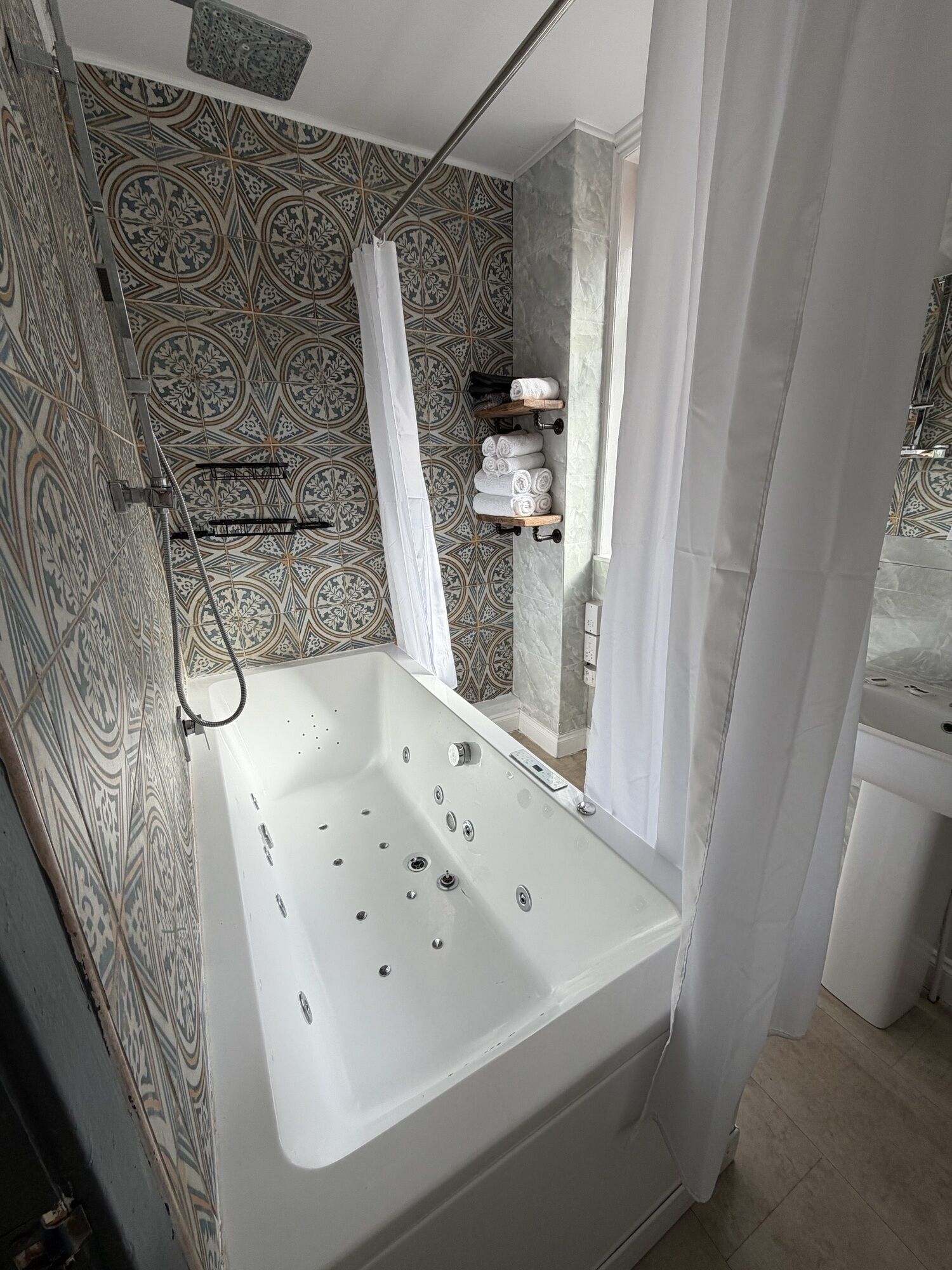A bathroom with a bathtub, shower, and patterned tiles.