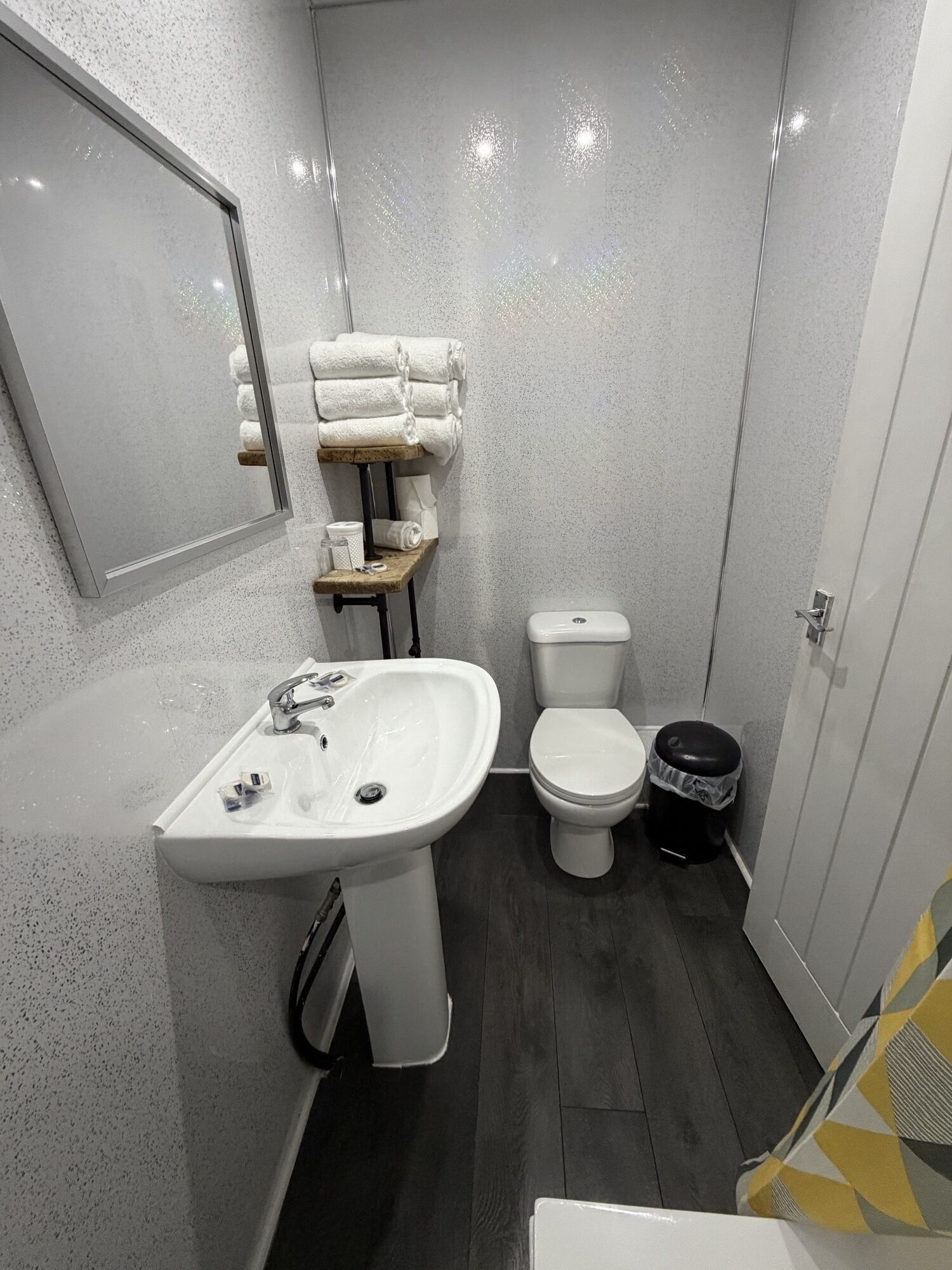 A compact bathroom with a white sink, a toilet, and a small trash bin.