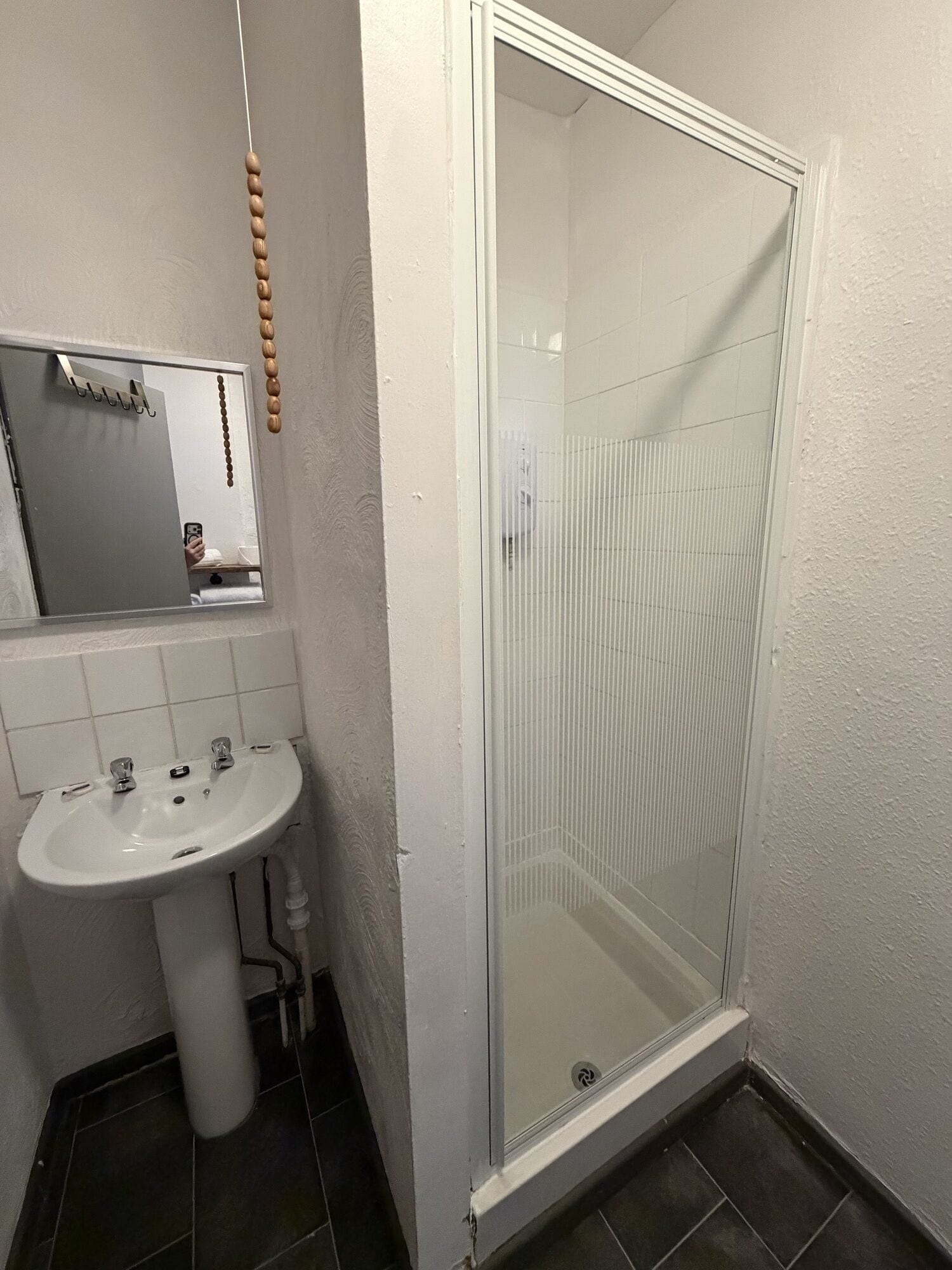 Un baño con lavamanos blanco, espejo y cabina de ducha de vidrio.