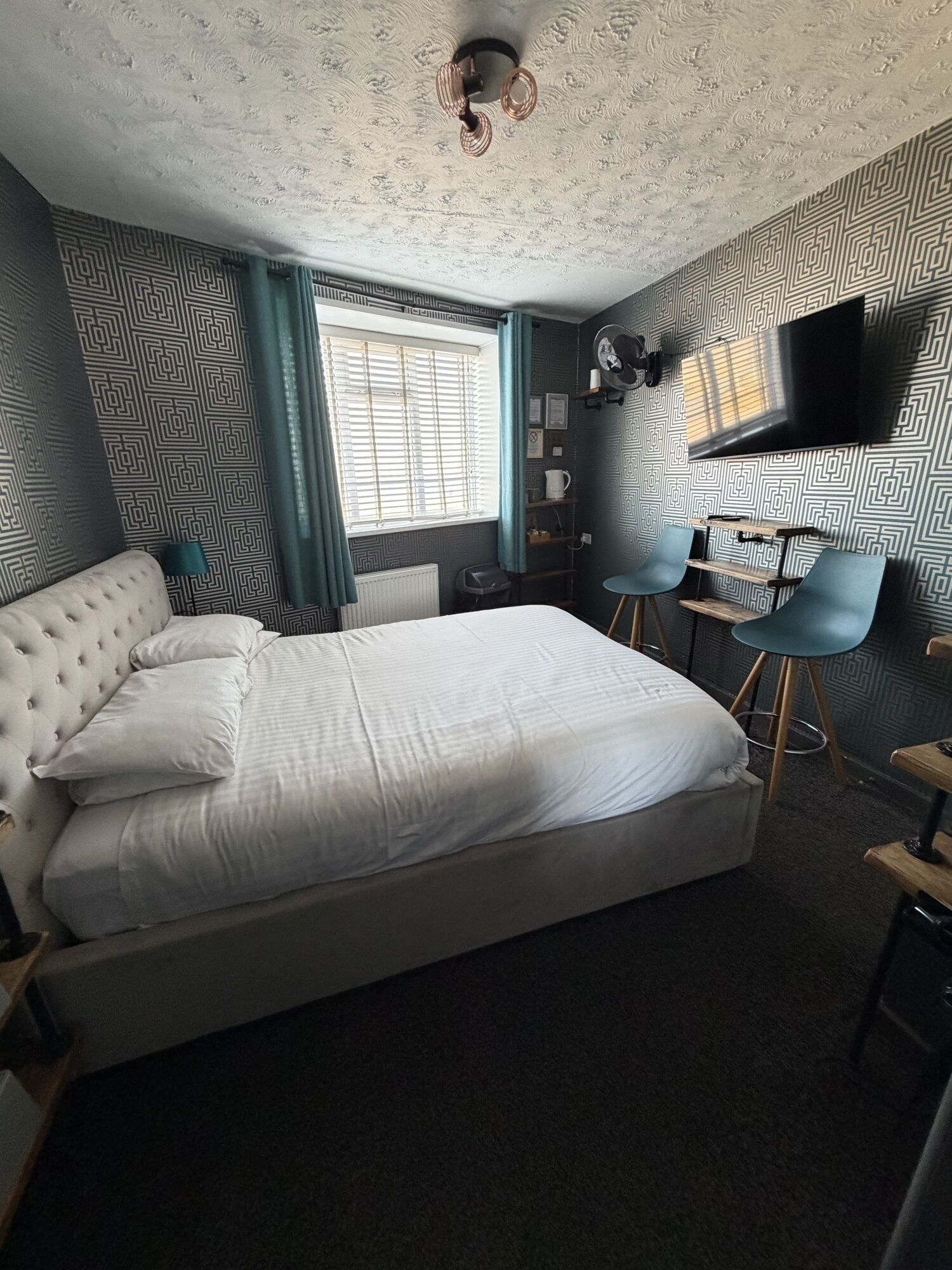 Un dormitorio con una cama grande, televisión y un escritorio con sillas.