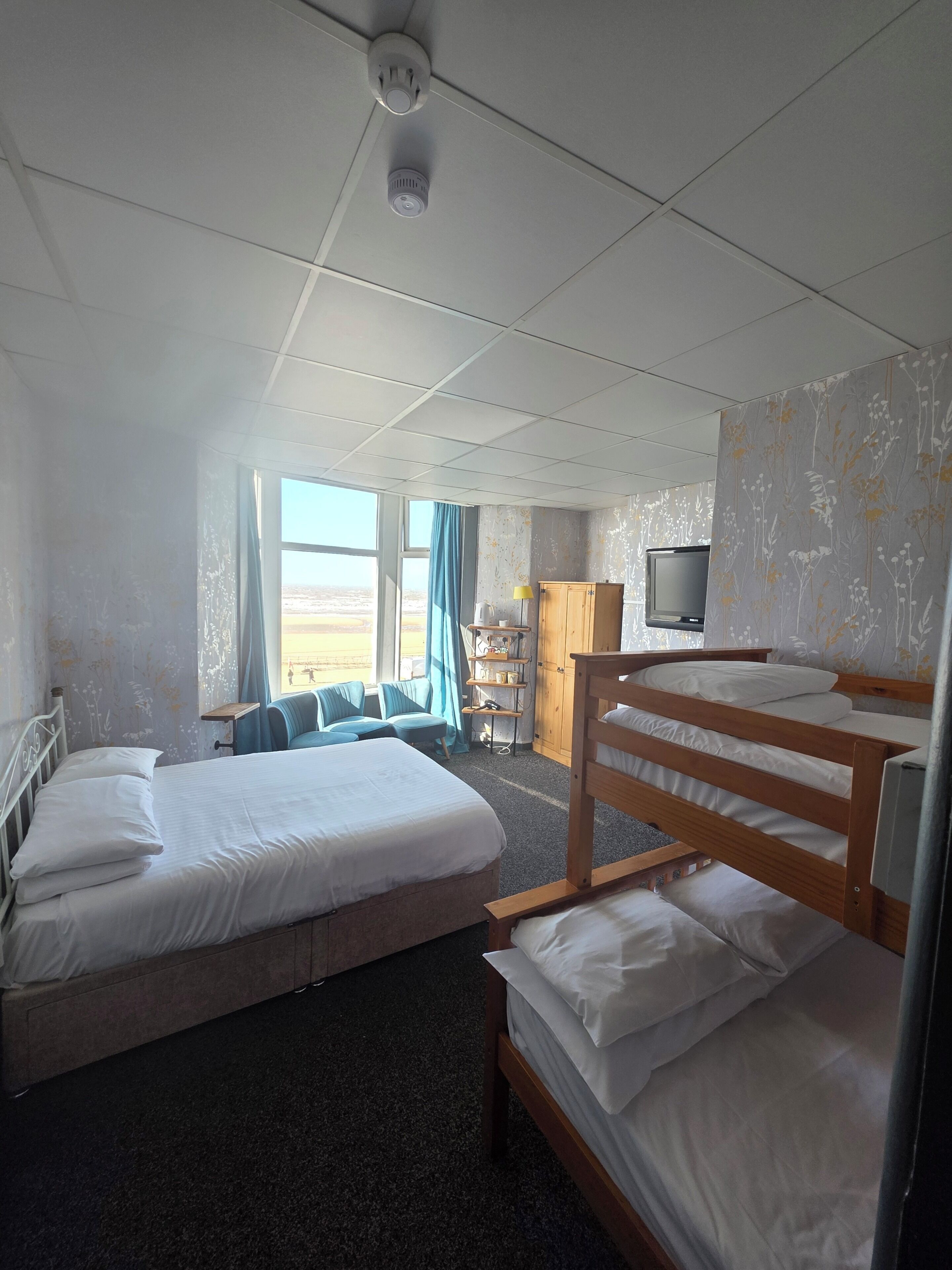 Une chambre d’hôtel avec deux lits, une télévision, un bureau avec une lampe et une vue sur l’extérieur.