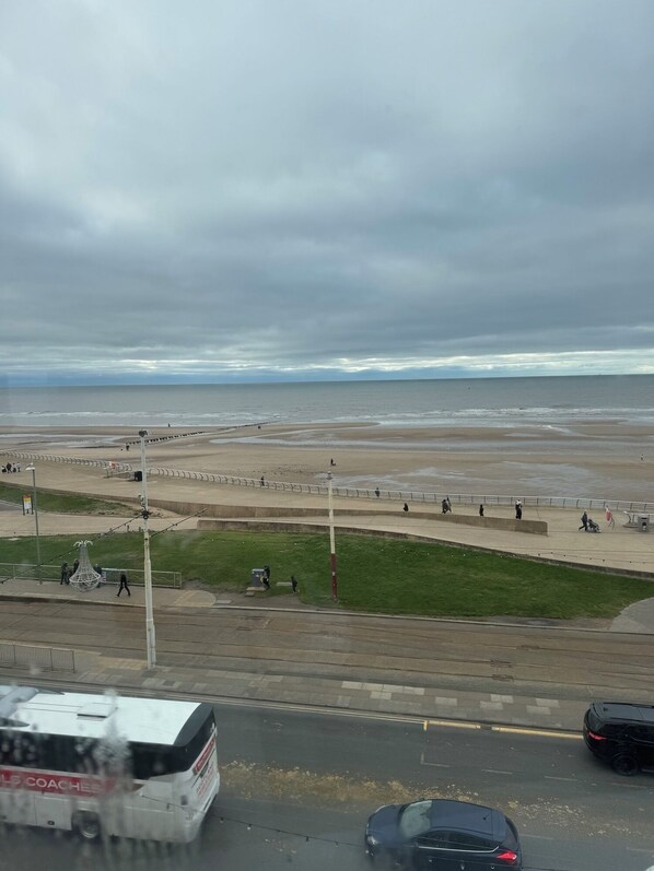 A coastal road with a beach in the background, a bus, and cars on the road. - Vinnies Family Hotel (Blackpool)