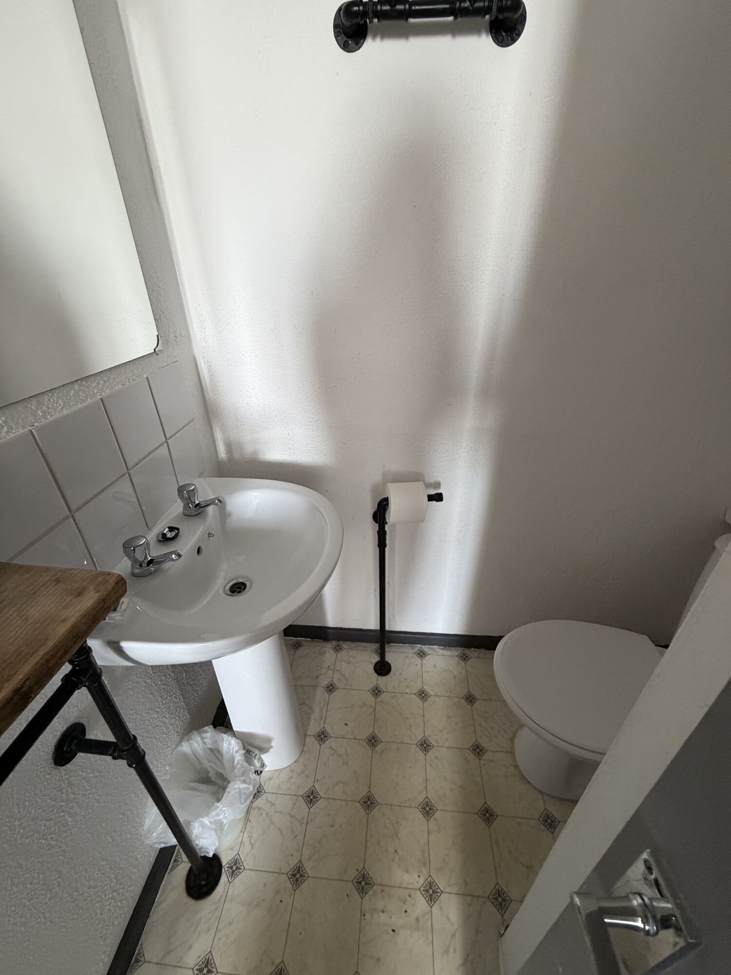 A small bathroom with a white sink, toilet, and a shower area.