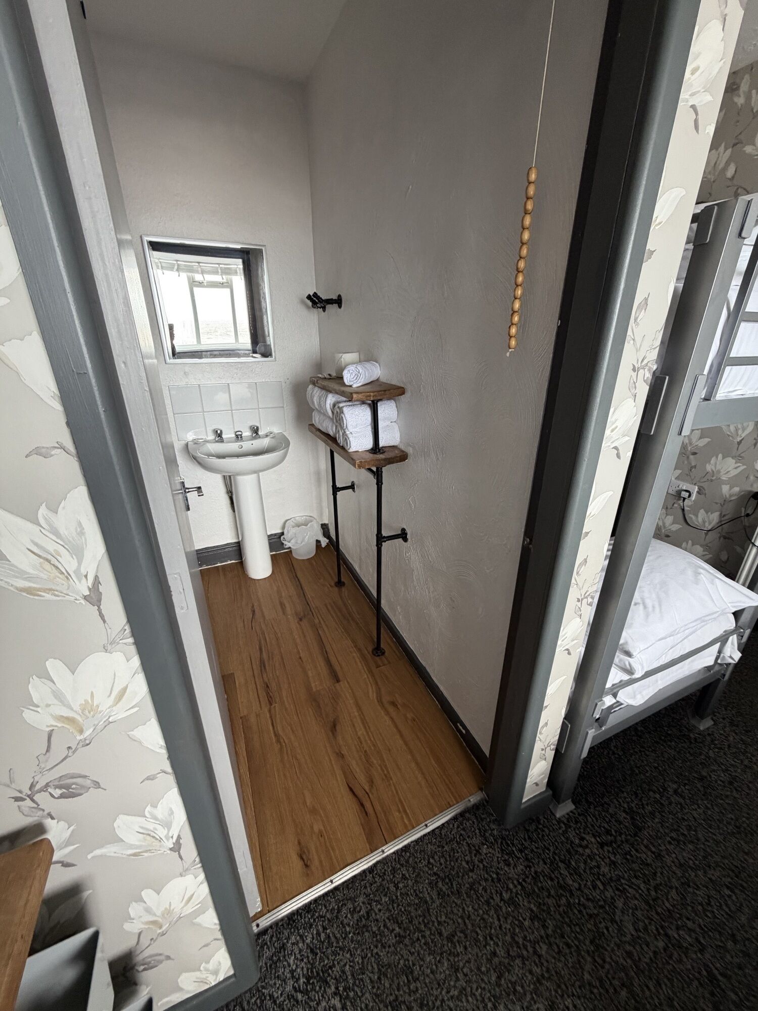 A compact bathroom with a sink, a mirror, and a towel rack.