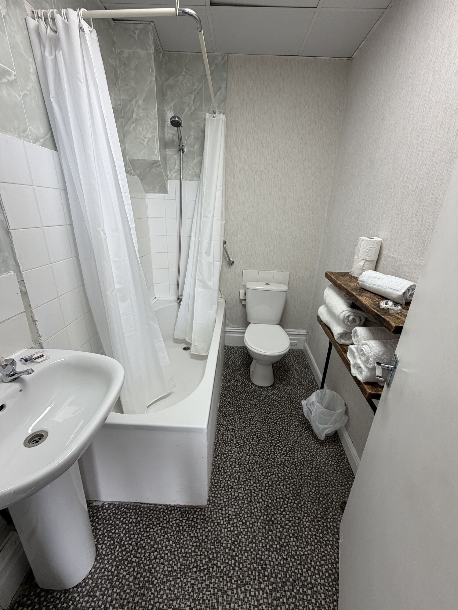 Une salle de bain équipée d’une baignoire, de toilettes, d’un lavabo et d’un rideau de douche.