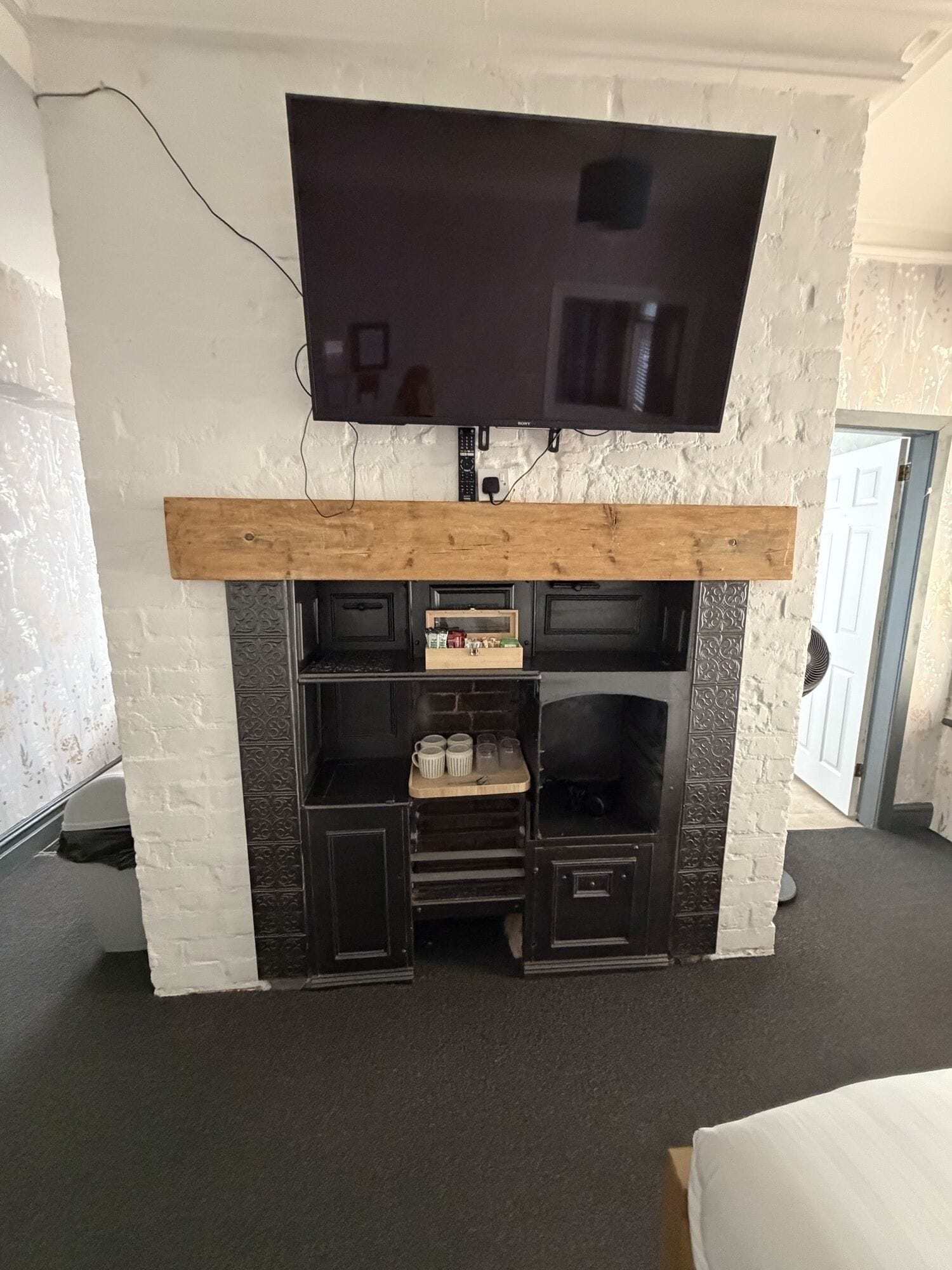 Une pièce dotée d’un téléviseur à écran plat fixé au-dessus d’une cheminée en bois.