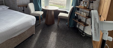 Una camera d'hotel con un letto, due poltrone, un tavolino, un pianoforte e vista mare.