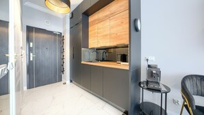 A modern kitchen with a wooden backsplash, a built-in oven, and a coffee machine. - Apartamenty Sun & Snow Lividus (Swinoujscie)