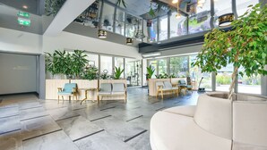 A modern lobby with seating areas, large windows, and indoor plants. - Apartamenty Sun & Snow Lividus (Swinoujscie)
