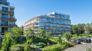 A multi-story residential building with balconies, surrounded by greenery and parked cars. - Apartamenty Sun & Snow Lividus (Swinoujscie)