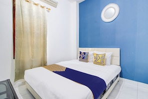 Un dormitorio con una cama, cabecera, espejo en la pared y cortina.