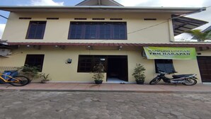 Un bâtiment à deux étages sur lequel est apposée une enseigne indiquant : « KAMPUNG LITERASI TBM HARAPAN ».