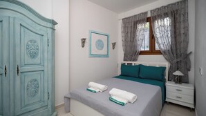 Un dormitorio con cama, mesita de noche, cómoda y ventana con cortinas.