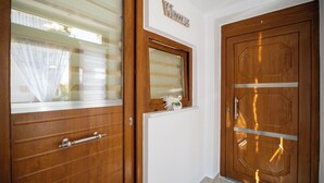 Una puerta de madera con un ventanal, un letrero de bienvenida encima y un pequeño adorno en el alféizar.