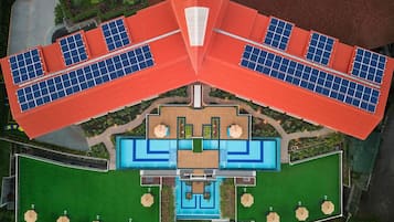 A modern hotel with a central swimming pool, multiple guest rooms, and solar panels on the roof.