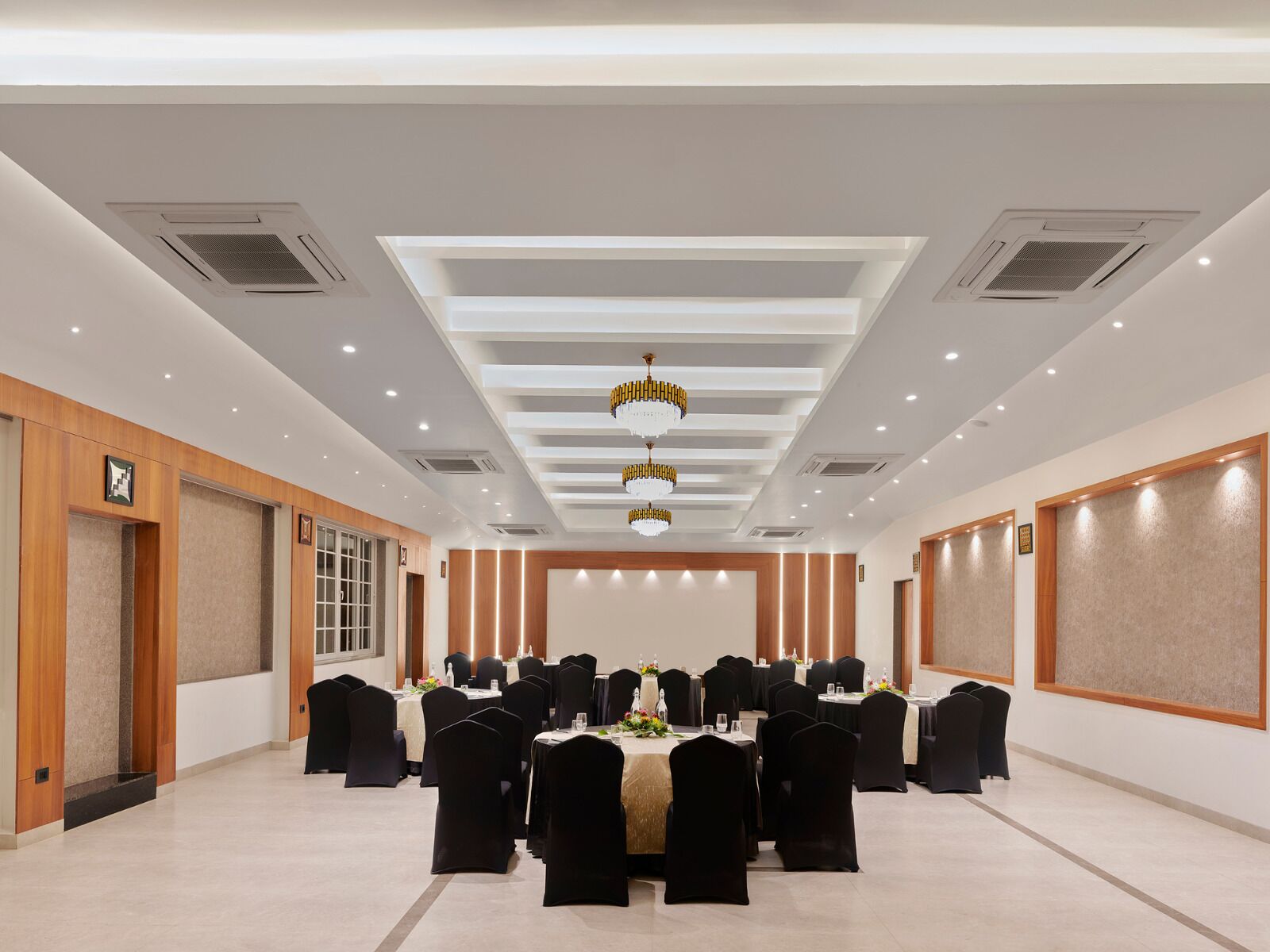 A conference room with tables and chairs, recessed lighting, and a modern ceiling design.