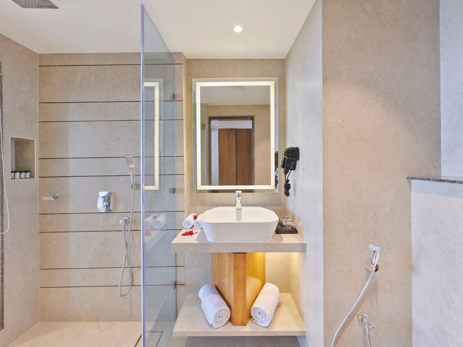A modern bathroom with a glass shower enclosure, a built-in sink, and a mirror above the vanity.