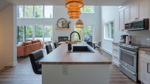Eine moderne Küche mit Kochinsel, großen Fenstern und einer Essecke mit einer Couch.