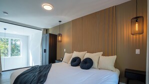 Ein modernes Schlafzimmer mit einem großen Bett, einer Wand aus Holzlamellen und einer hängenden Leuchte.