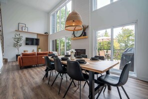 Un comedor moderno con una mesa de madera, sillas negras y una lámpara colgante de fibra.