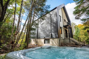 Una casa moderna con jacuzzi en un área boscosa.