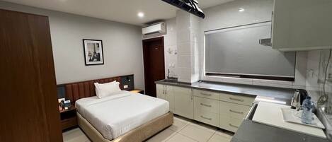 Une chambre d’hôtel moderne équipée d’un lit, d’une kitchenette et d’une salle de bain.