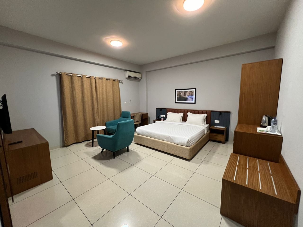 A hotel room with a bed, a desk, a chair, a wardrobe, and a television.