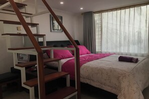 A bedroom with a bed, a staircase, a window with curtains, and a framed picture on the wall. - OYO 94320 Homestay Abah Hank Syariah (Yogyakarta)
